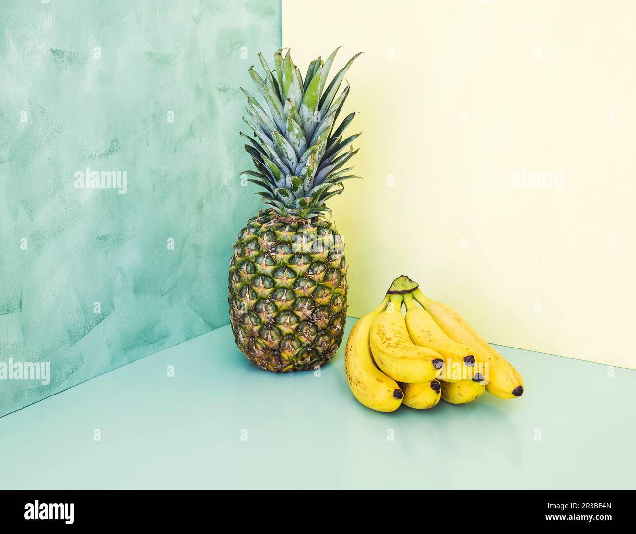 Ganze Ananas und Bananen auf gelbem und grünem Hintergrund Stockfoto