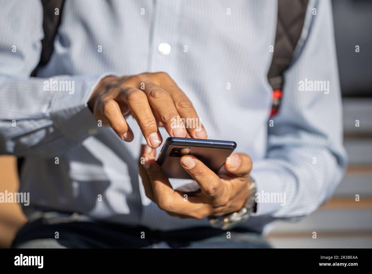 Details der Hände eines Latino-Mannes, der ein Mobiltelefon benutzt, von vorne gesehen. Stockfoto