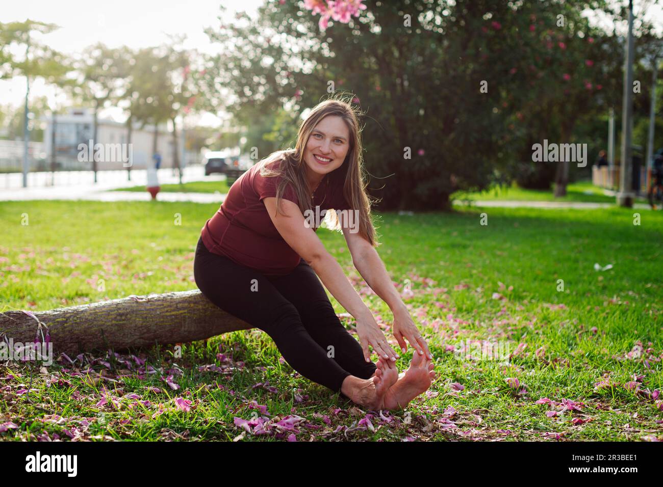 Lächelnde schwangere Frau, die sich auf dem Rasen ausstreckt Stockfoto