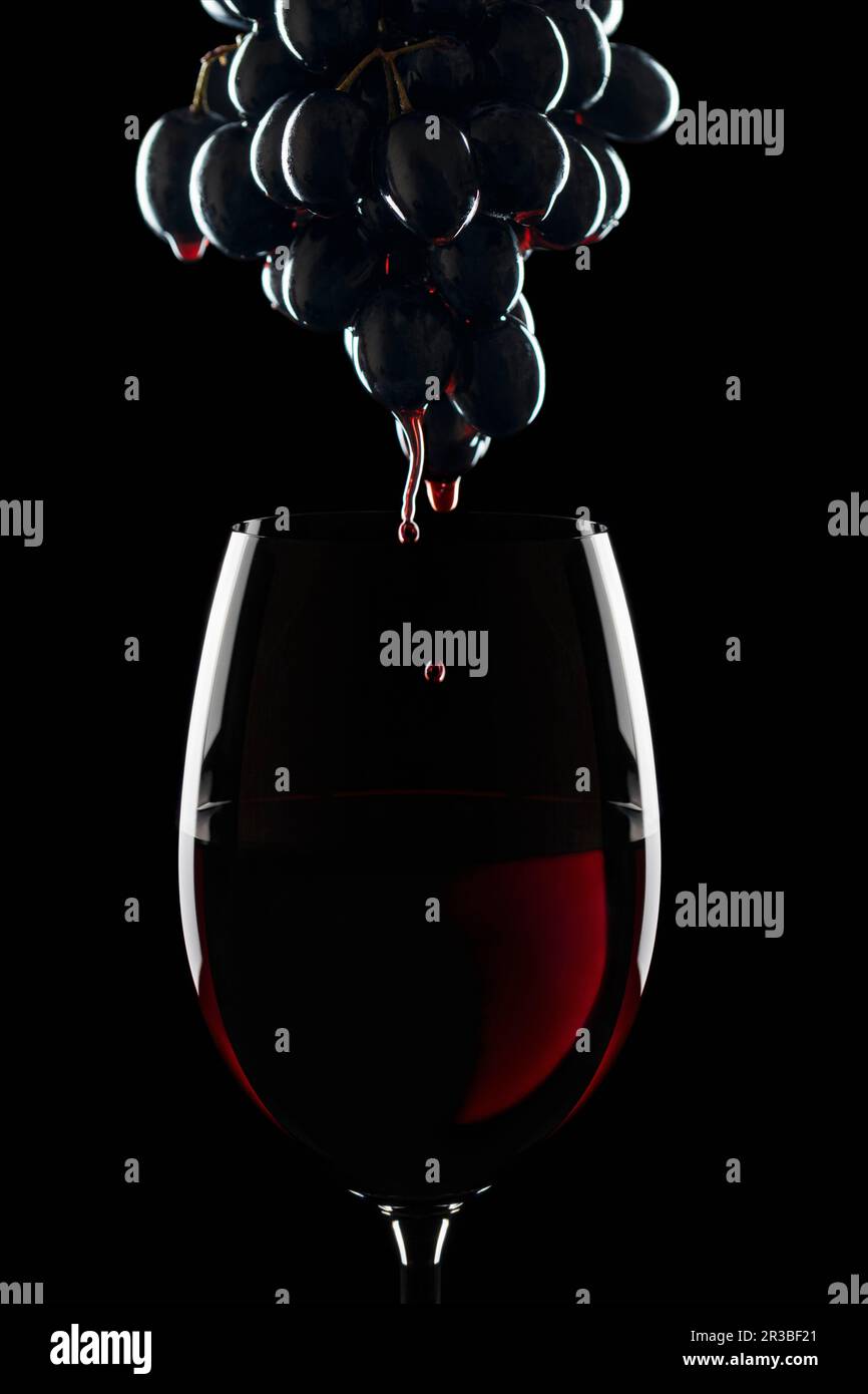 Ein Glas Rotwein und ein paar rote Weintrauben Stockfoto