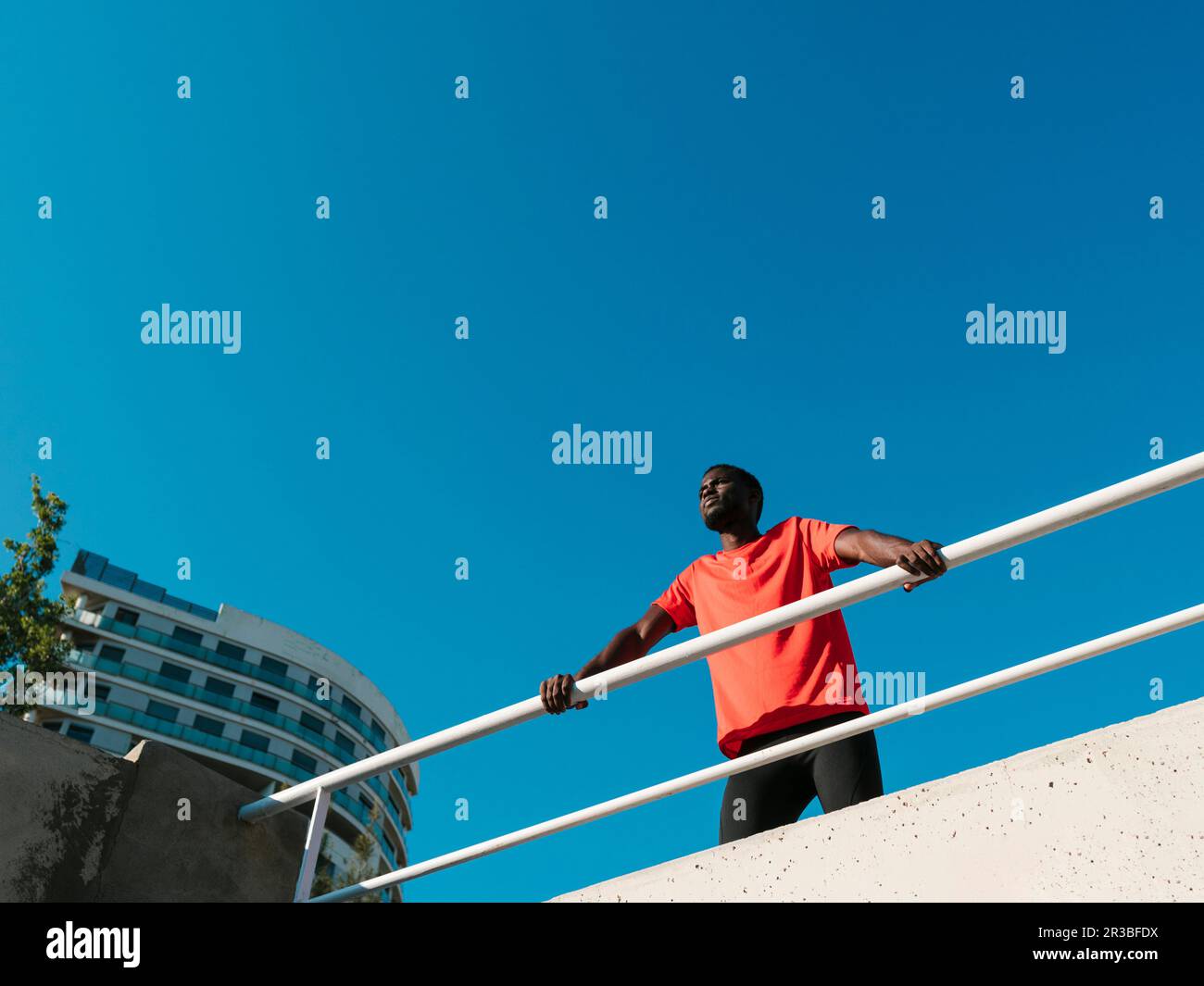 Ein Athlet steht neben dem Geländer unter klarem blauen Himmel Stockfoto