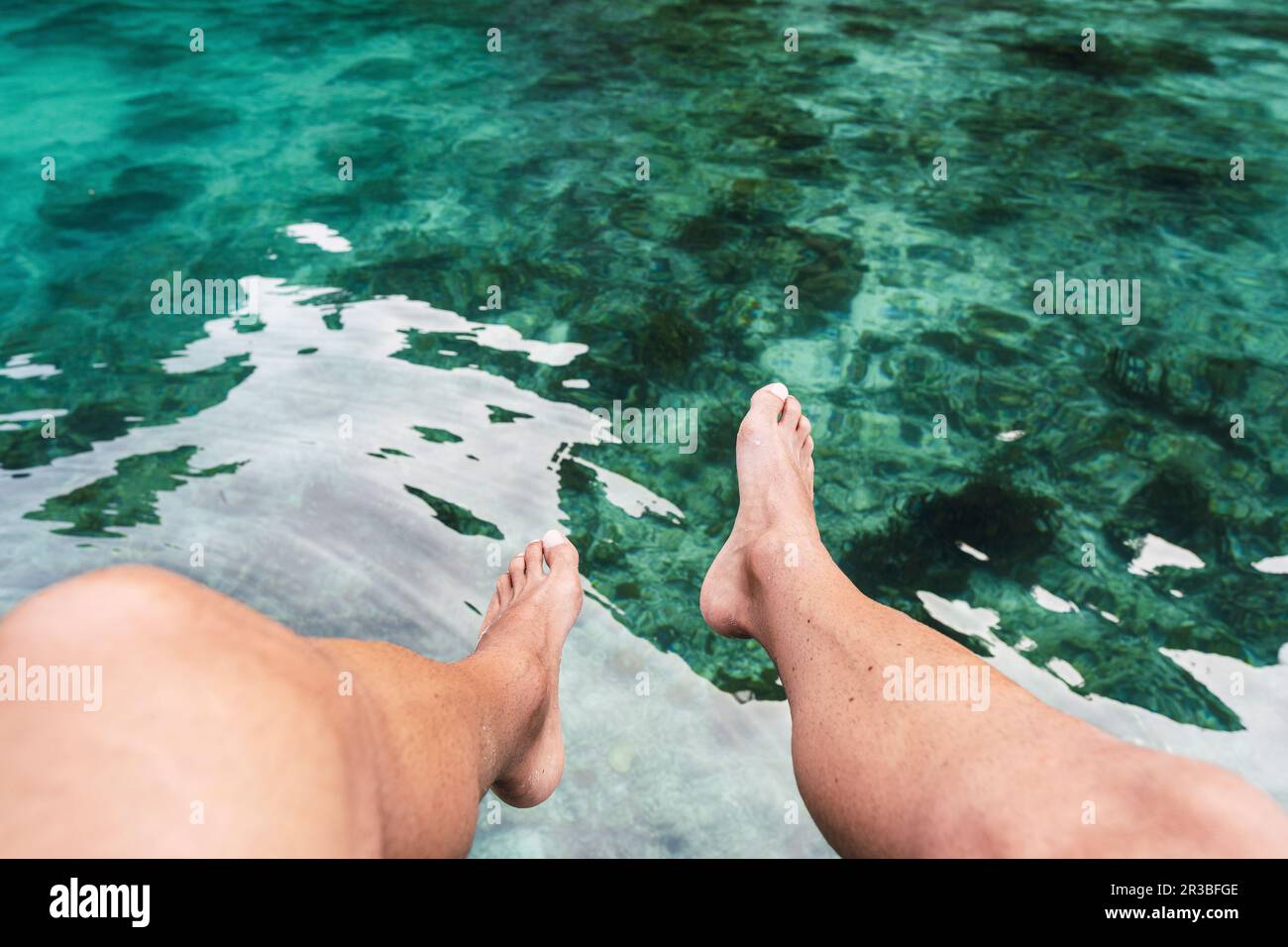 Beine eines Mannes über dem Meer im Urlaub Stockfoto
