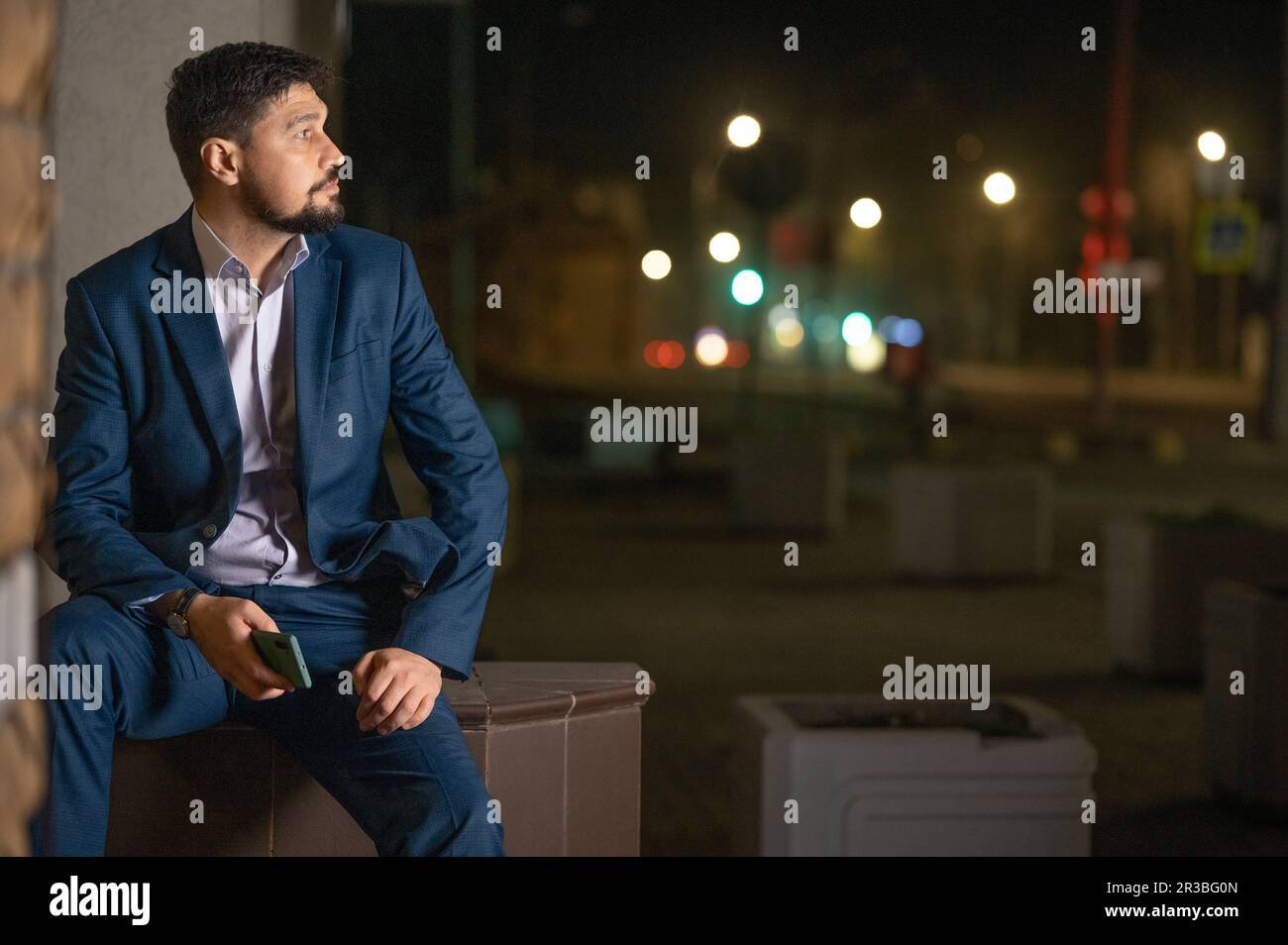 Nachdenklicher Geschäftsmann, der nachts auf dem Sitz sitzt Stockfoto