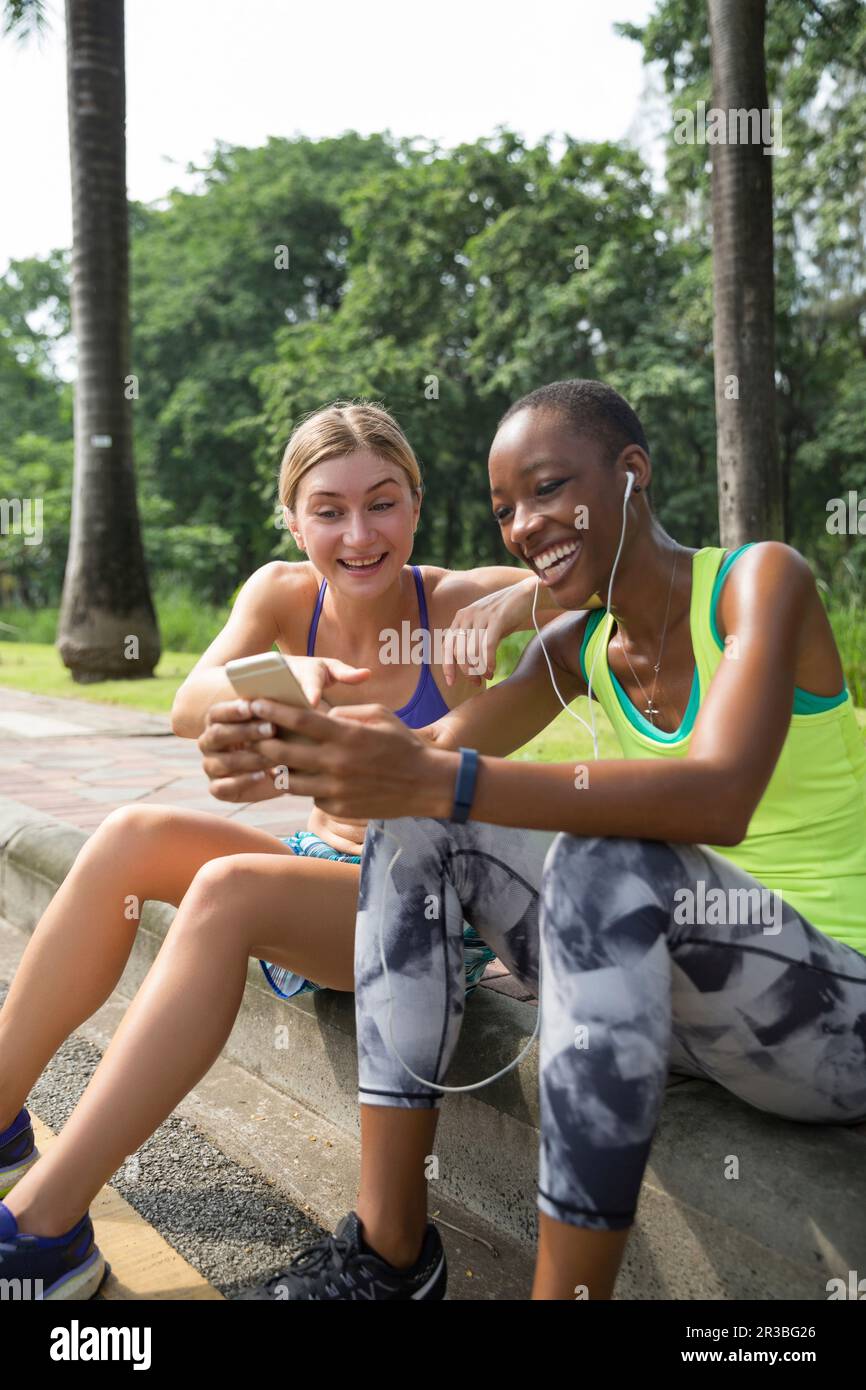 Fröhliche Freunde teilen ihr Smartphone im Park Stockfoto