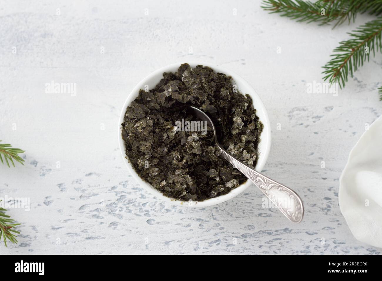 Gehackte Nori-Blätter in einer weißen Schüssel auf hellblauem Hintergrund. Kochschritt von veganem schwarzen Kaviar aus Chiasamen Stockfoto