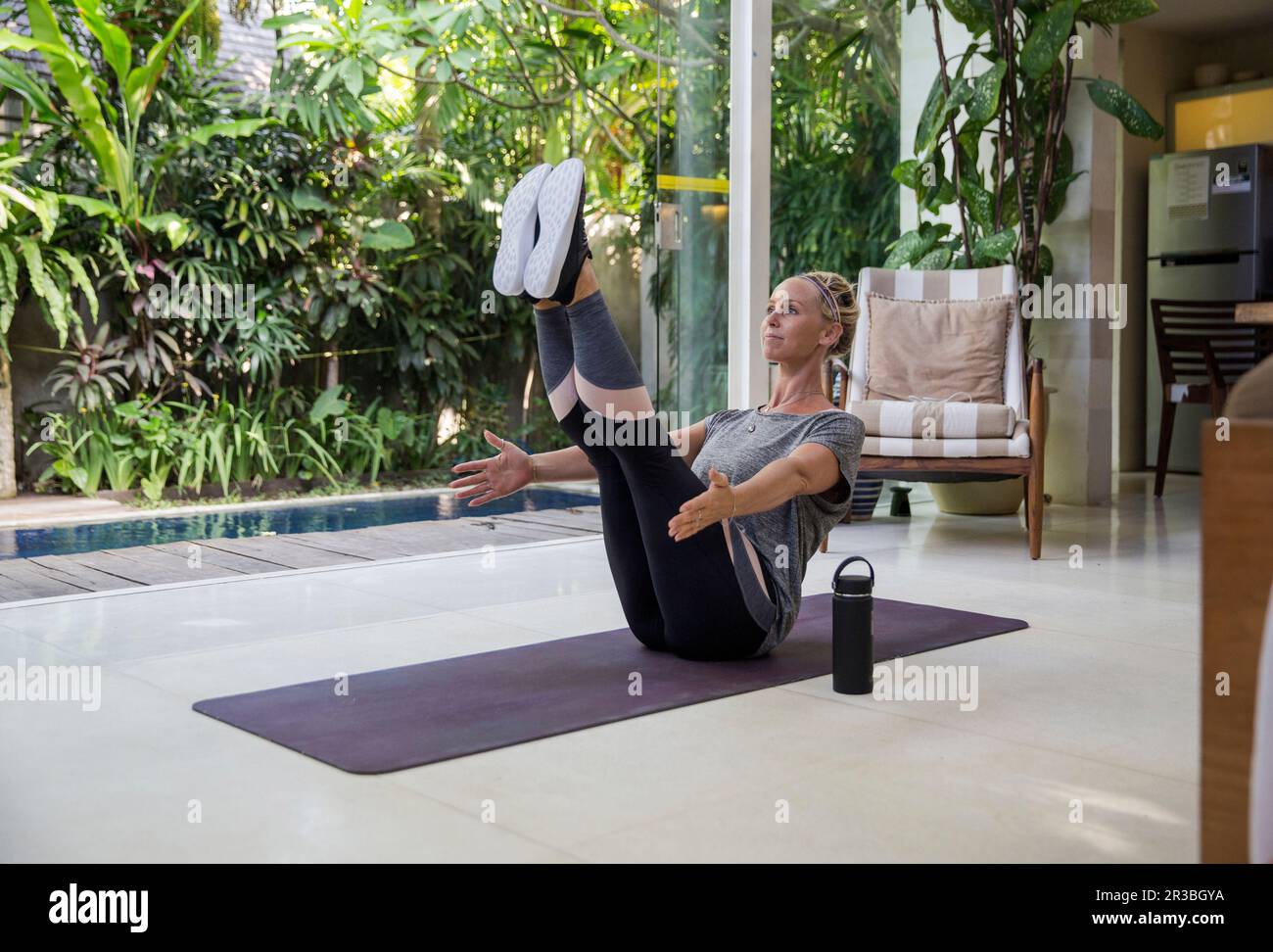 Frau, die zu Hause auf Yoga-Matte trainiert Stockfoto
