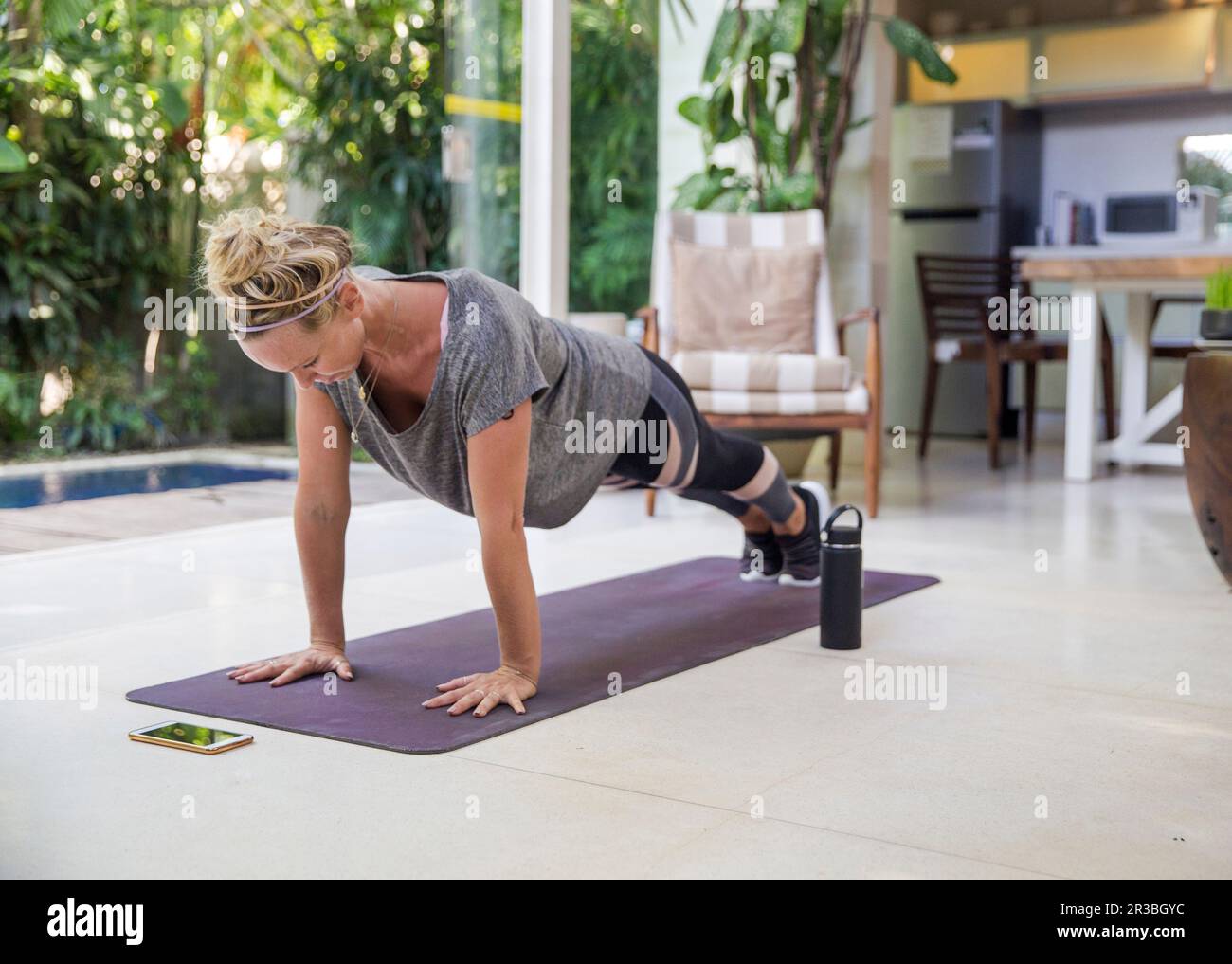 Frau, die zu Hause auf einer Yogamatte trainiert Stockfoto