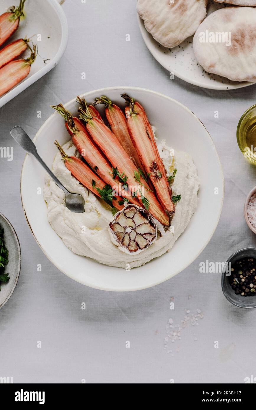 Hummus mit gerösteten Karotten, Pitta-Brot und Knoblauch Stockfoto