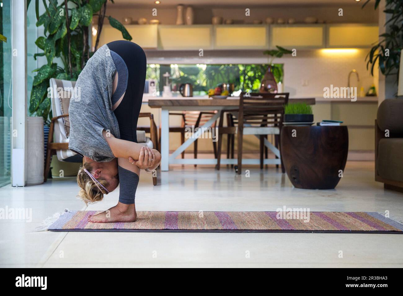 Eine Frau, die zu Hause im Wohnzimmer die große Zeh-Pose praktiziert Stockfoto