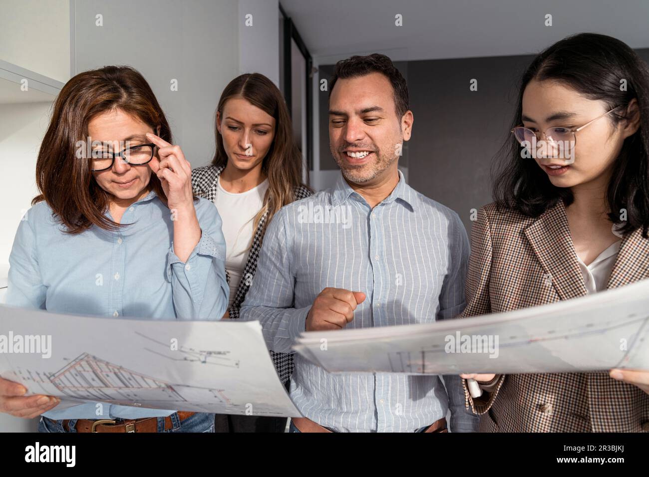 Geschäftsleute, die im Büro stehen und Architekturpläne haben Stockfoto