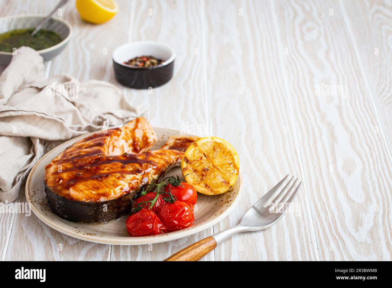 Gegrilltes Lachssteak mit Teriyaki-Sauce, Tomaten und Zitrone Stockfoto