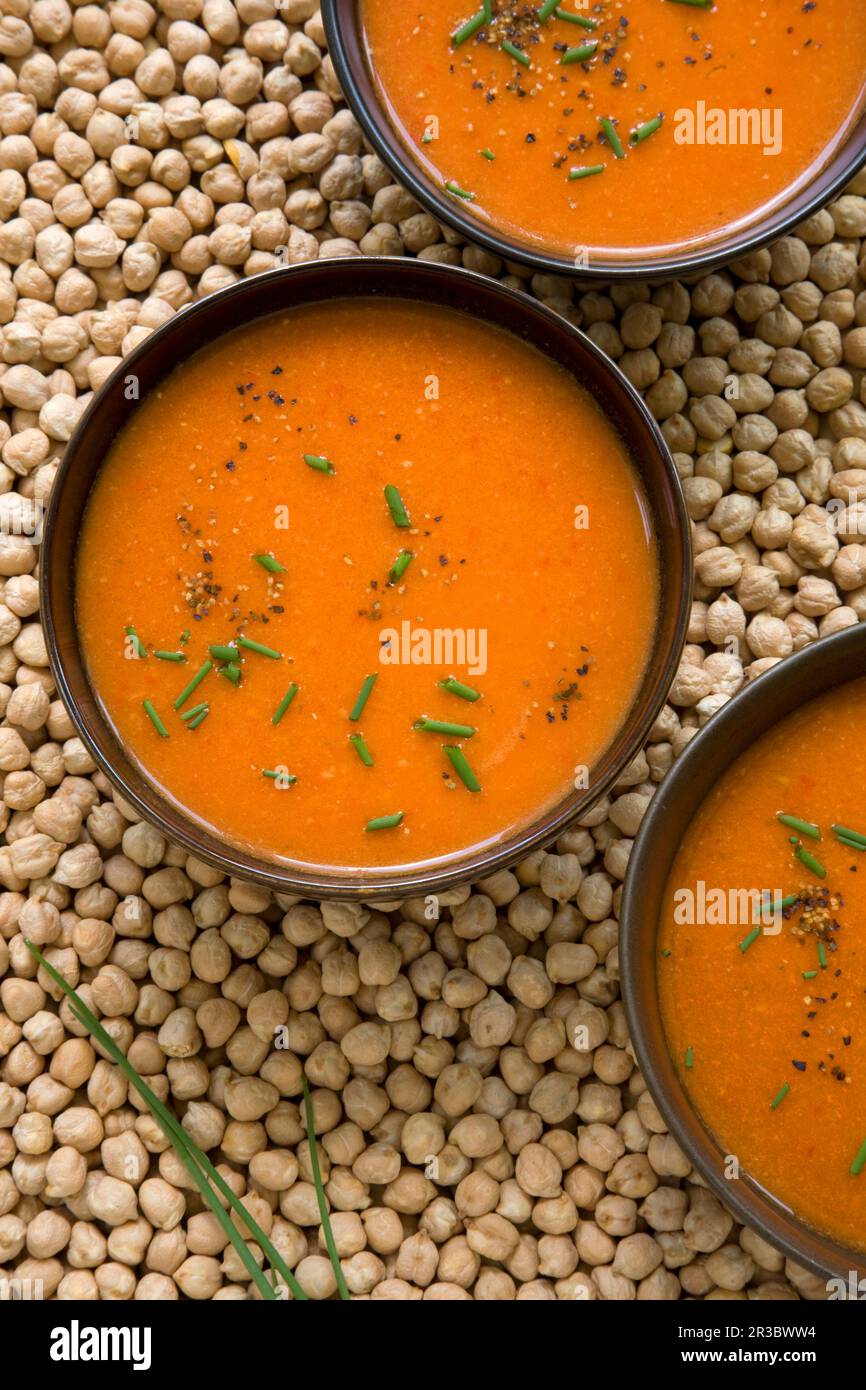 Geröstete Tomaten- und rote Pfeffersuppe auf dem Hintergrund getrockneter Kichererbsen Stockfoto