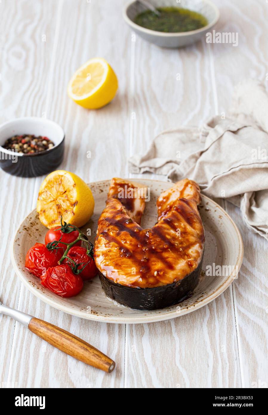 Gegrilltes Lachssteak mit Teriyaki-Sauce, Tomaten und Zitrone Stockfoto