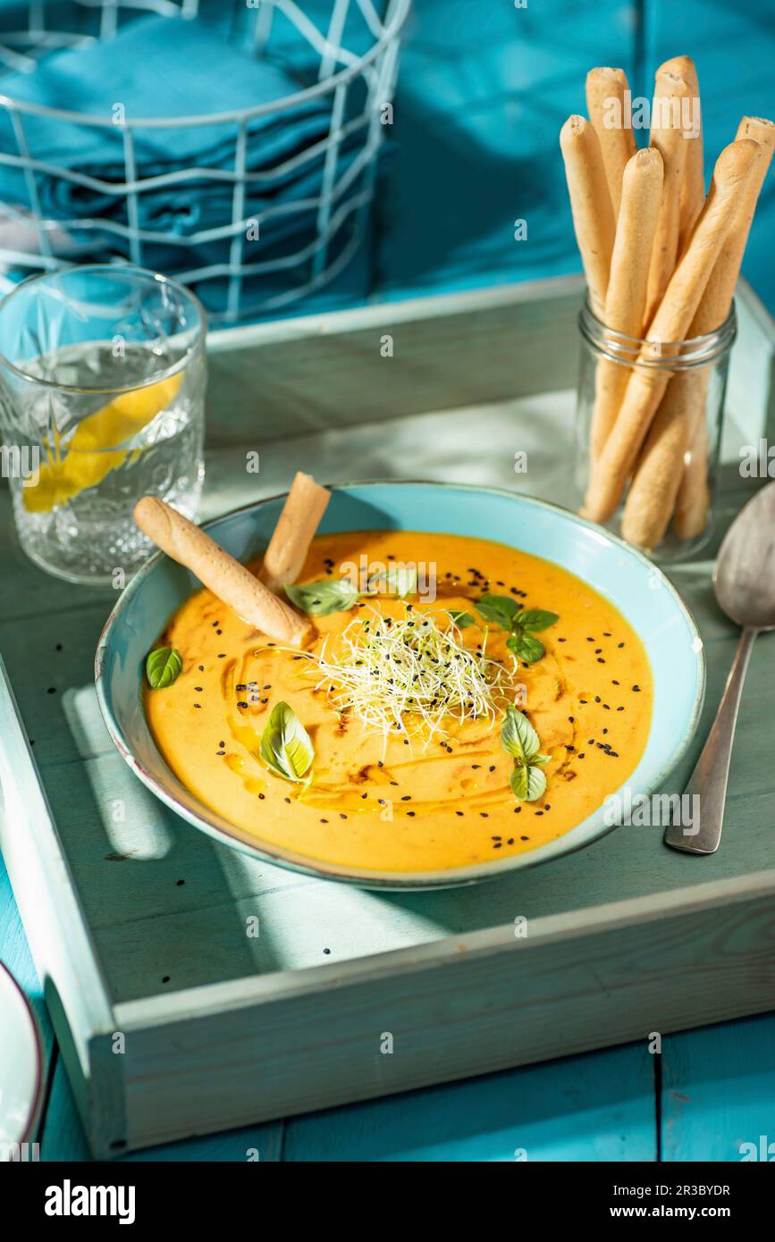 Gelbe Tomatencremesuppe mit Lauch-Sprossen, Basilikum und schwarzem Sesamgarn Stockfoto