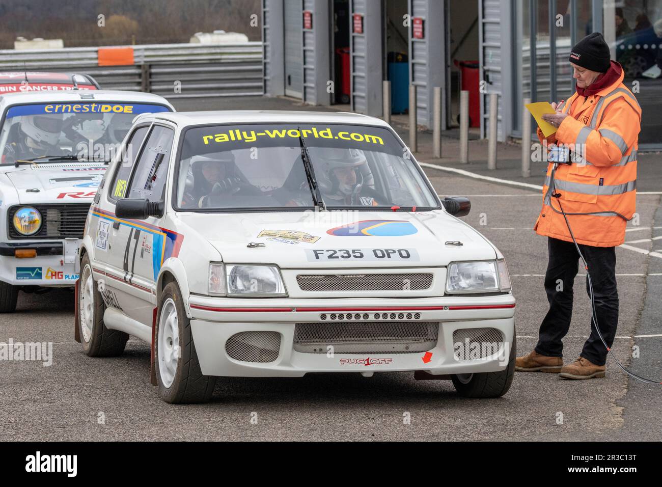 Ross Wey und Liam Carfrae in ihrem 1988 Peugeot 205 mit dem Kontrollpunkt Marshal während der Snetterton Stage Rally 2023, Norfolk, Großbritannien. Stockfoto