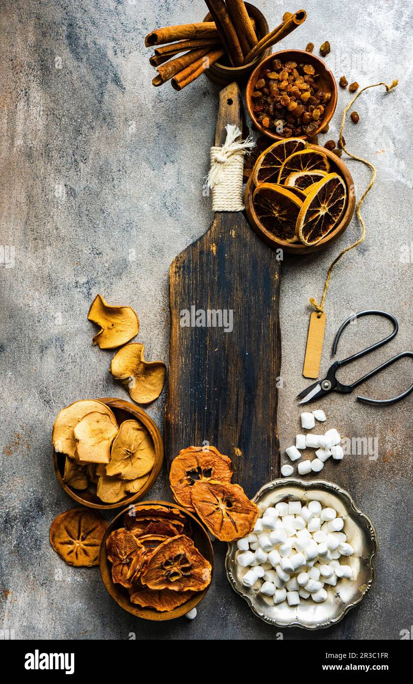 Getrocknete Früchte, Mini-Marshmallows und Zimtstangen auf altem Holzbrett Stockfoto