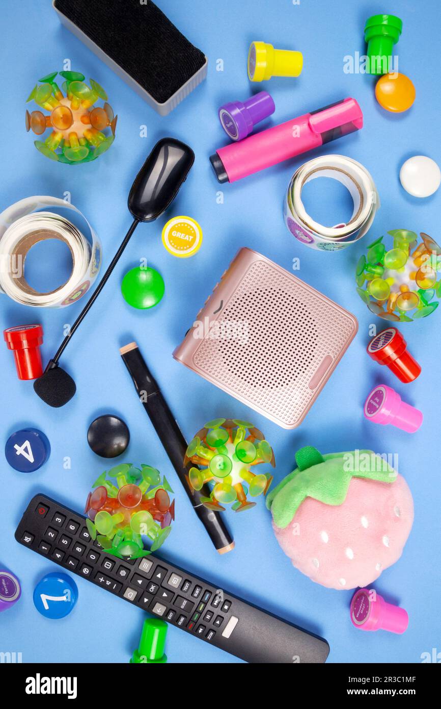 Kindergärtnerausrüstung, Spielzeug, Briefmarken, Marker, Aufkleber, Flaches Mikrofon. Farbenfrohe Lehrmittel für die Grundschule in einem vorbereiteten Klassenzimmer Stockfoto