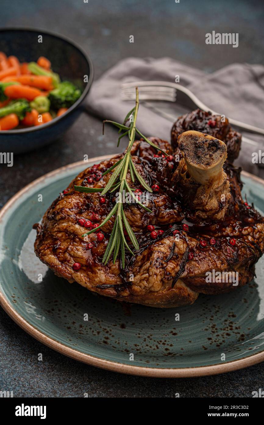 Köstliches geröstetes Schweinefleisch mit glasierter brauner knuspriger Haut, roten Pfefferbeeren und Rosmarin Stockfoto