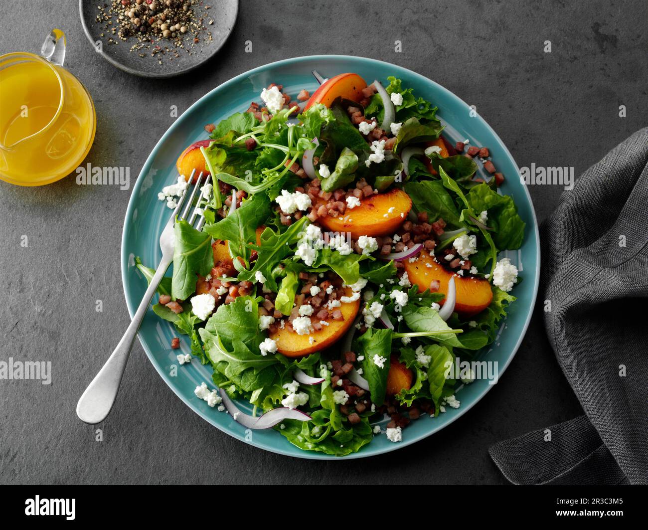 Gewürfelter Schinken- und Baby-Greens-Salat mit gegrillten Pfirsichscheiben und zerkleinerten Ziegenchees Stockfoto