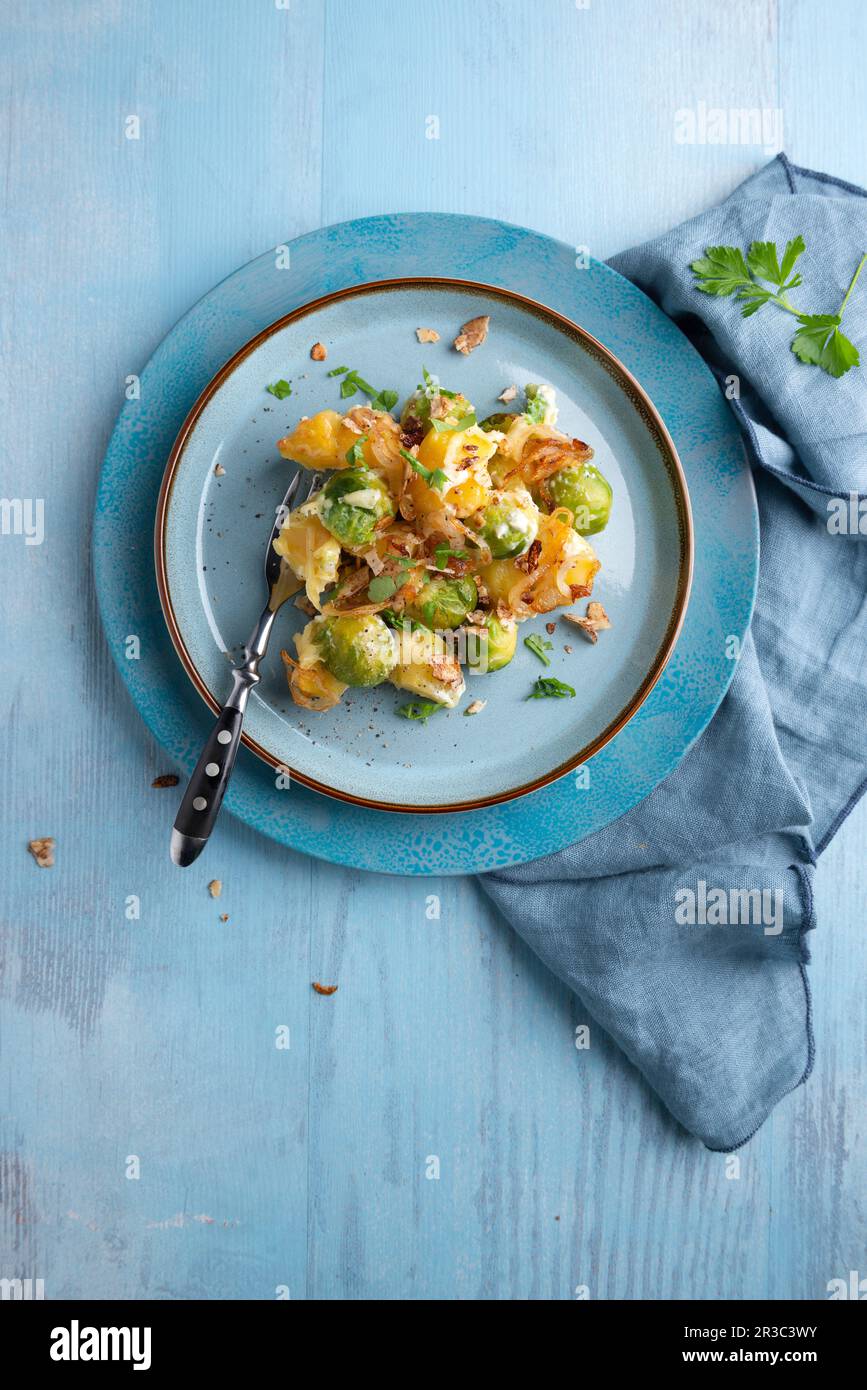 Vegane Kartoffeln und Rosenkohl backen mit gebratenen Zwiebeln und Teriyaki-Mandeln Stockfoto