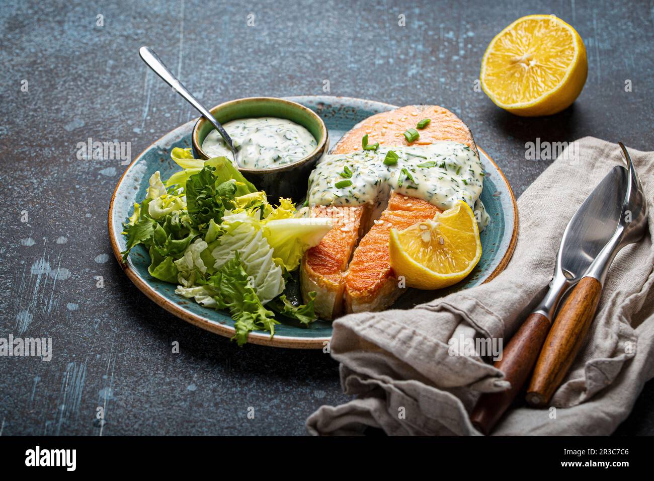 Gesundes Essen gekochtes Lachssteak vom Grill mit weißer Dillsauce und grünen Salatblättern Stockfoto