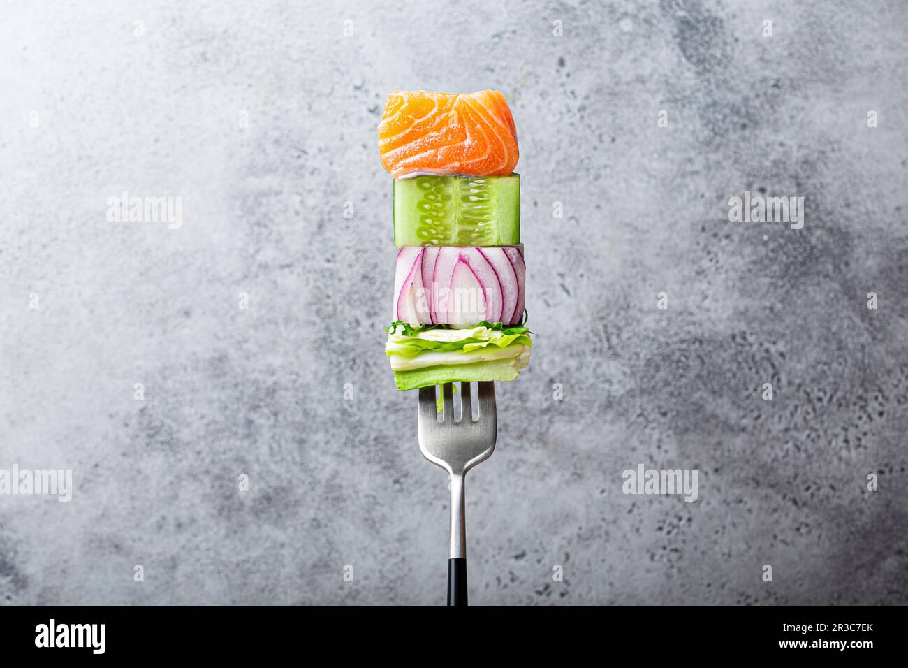 Nahaufnahme der Gabel mit Essen: Lachs, Gurke, Zwiebel, grüner Salat Stockfoto