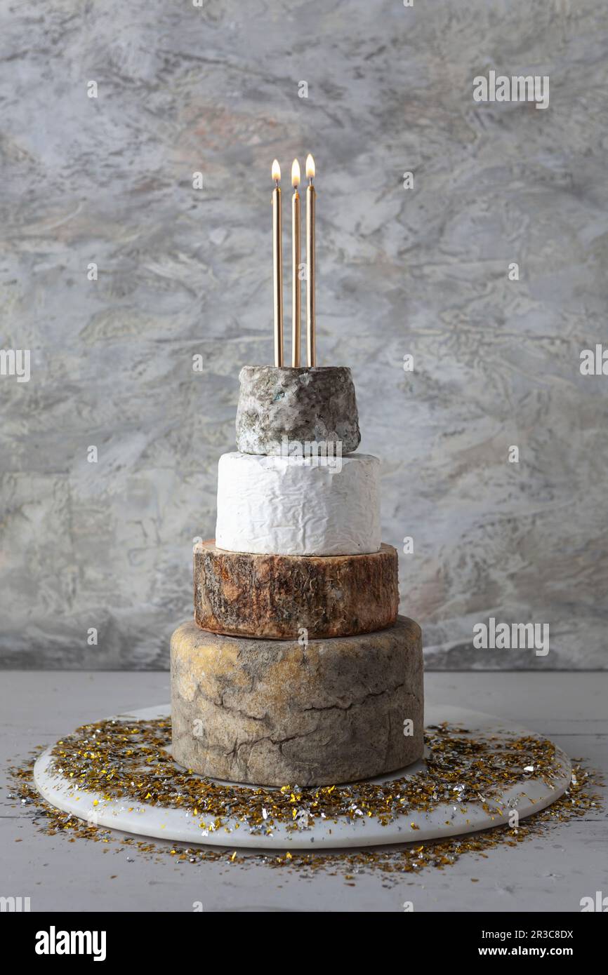 Cheese Wedding Cake – Käselaibe, die als mehrstufige Hochzeitstorte mit Kerzen und goldenen Kerzen angeordnet sind Stockfoto