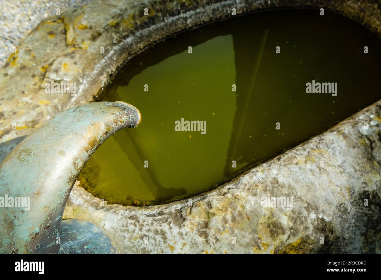 Ein alter Brunnen, verwittert von der Zeit, der aufwändige Handwerkskunst zeigt und ein nostalgisches Herzstück in Gärten oder Plätzen bietet. Stockfoto