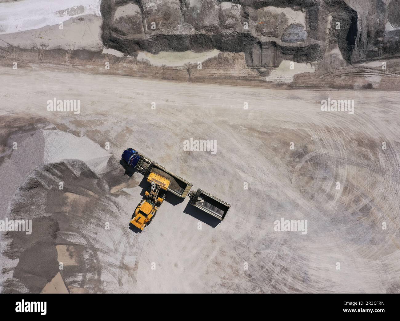 Blick aus der Vogelperspektive auf die Baustelle für Schüttgüter, abstrakt mit Frontlader-Lader-Lader bei einem Baustoffgroßhändler Stockfoto