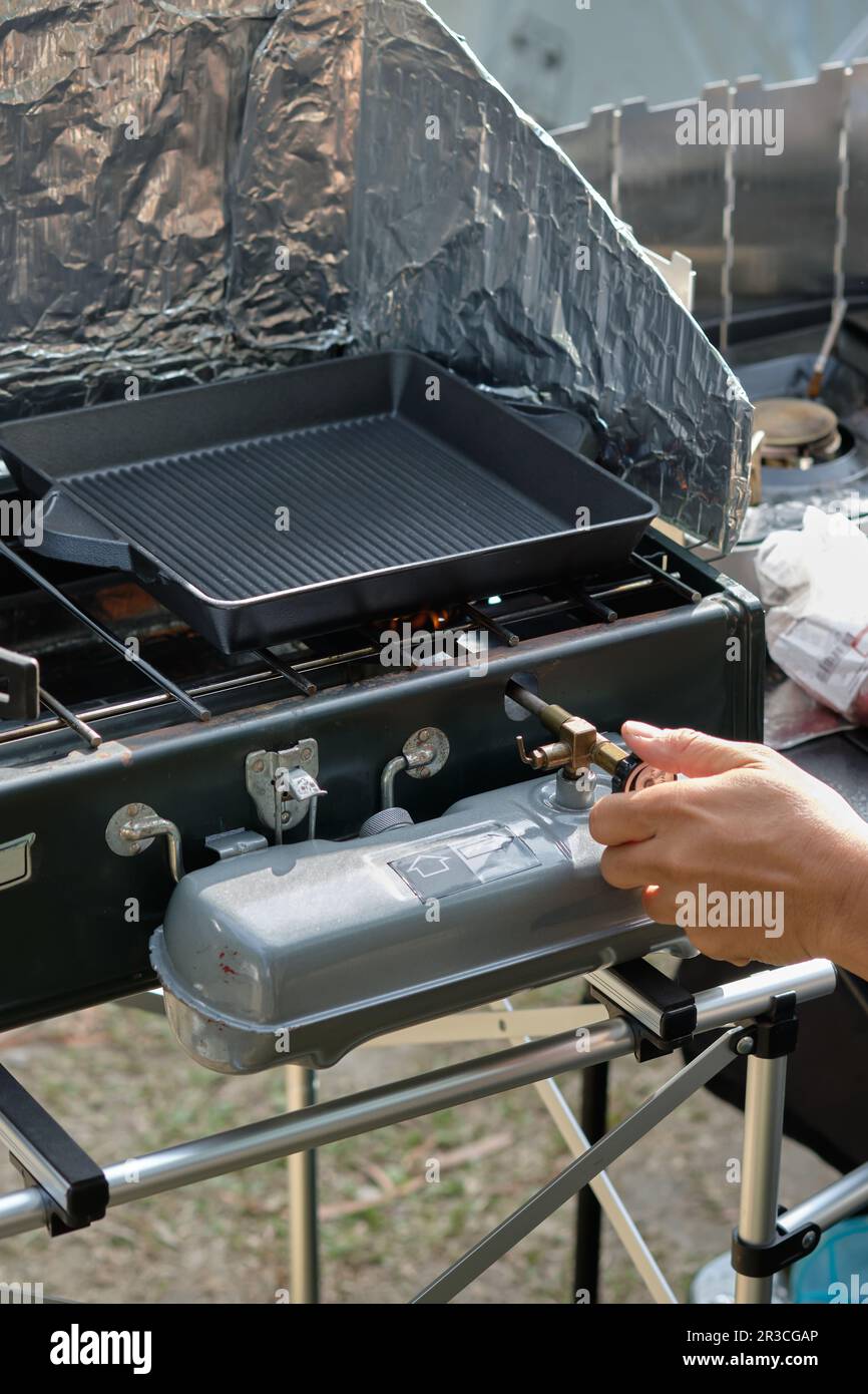 Nahaufnahme, leere Eisenkanne auf Campingofen, Powerhouse-Herd, Dual Fuel 2-Brenner, Camping Kochen in der Natur im Freien Stockfoto