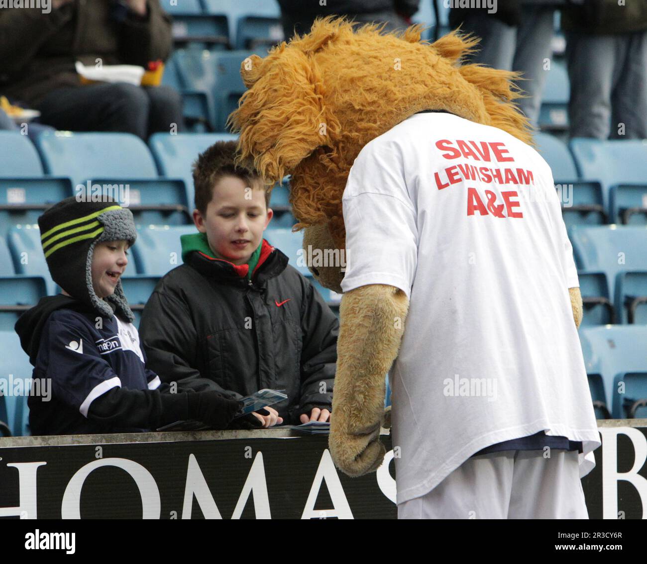 Millwall Maskottchen trägt ein T-Shirt, das Save Lewisham A&E Autogramme für die jungen Fans unterstützt. Das Spiel hat den Turm Millwall FC 10/03/13 Mi beendet Stockfoto