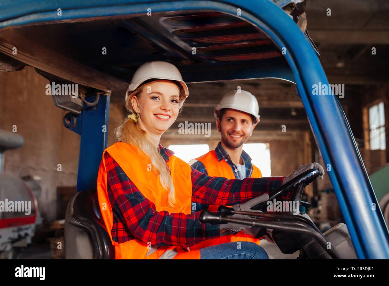 Glückliche Gabelstaplerfahrerin lächelt und schaut auf die Kamera Stockfoto