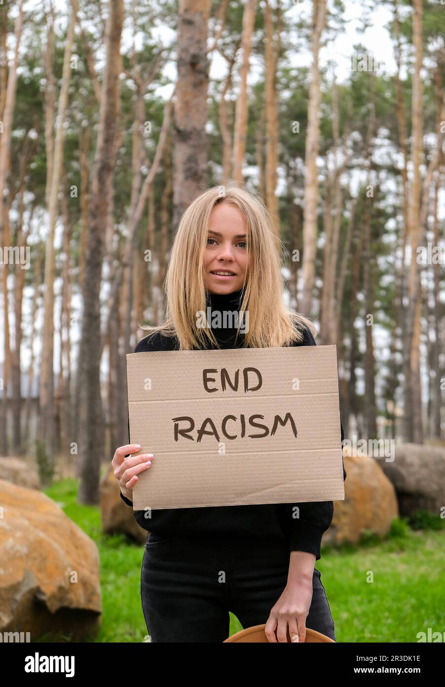 Porträt einer weissen jungen Frau im Hut mit Pappe und Text im Freien. Naturhintergrund. Protestaktivist Stockfoto