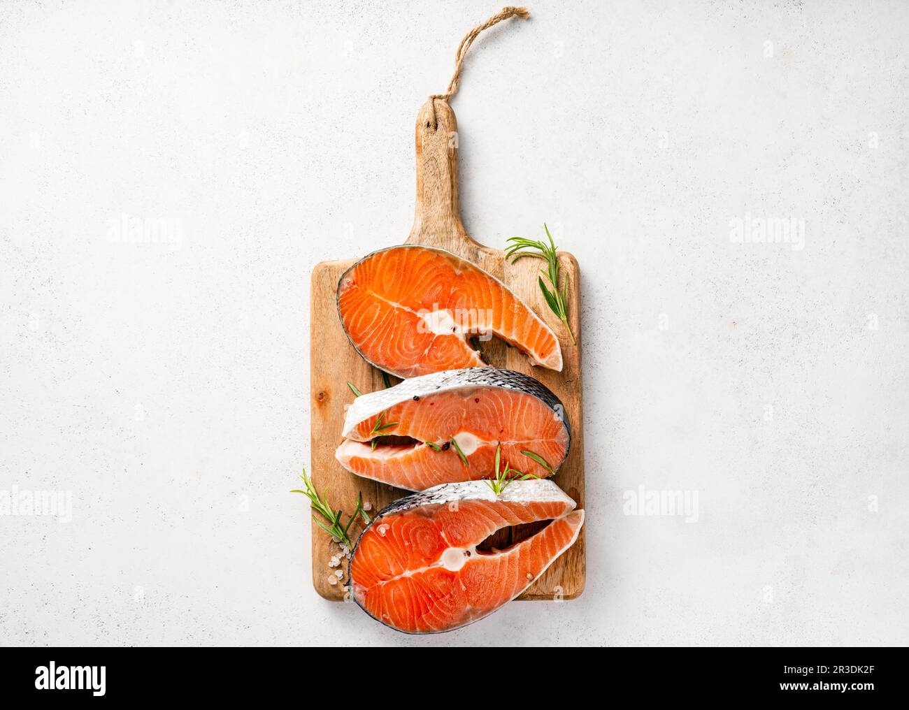 Frische rohe Lachssteaks auf Holzbrett. Draufsicht auf Fische auf weißem Hintergrund. Stockfoto