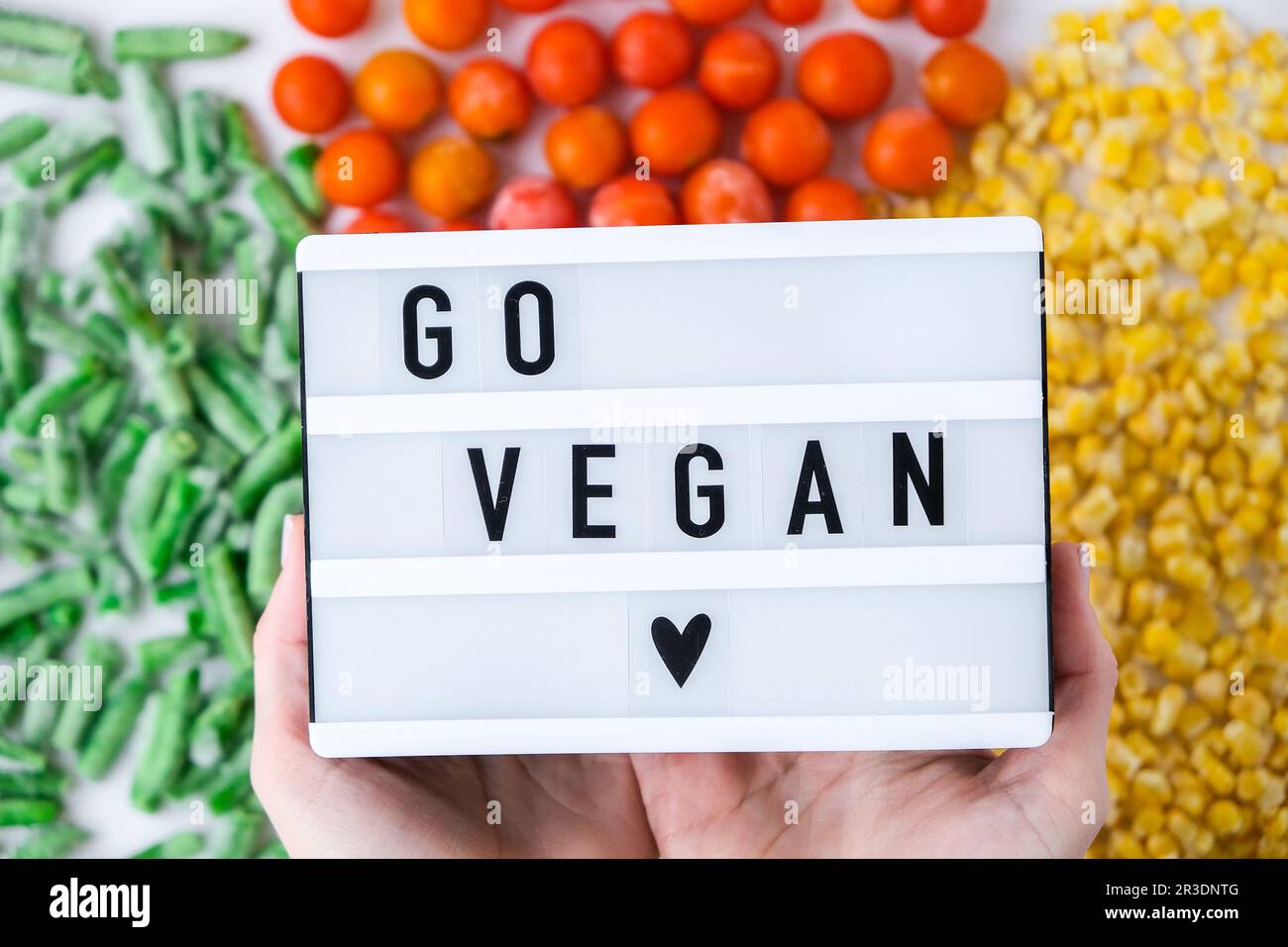 Lightbox mit Text GO GO VEGAN Frozen Gemüsesoße aus gelbem Mais, grünen Bohnen, roten Tomaten. Farben der Ampel. Ernte F Stockfoto