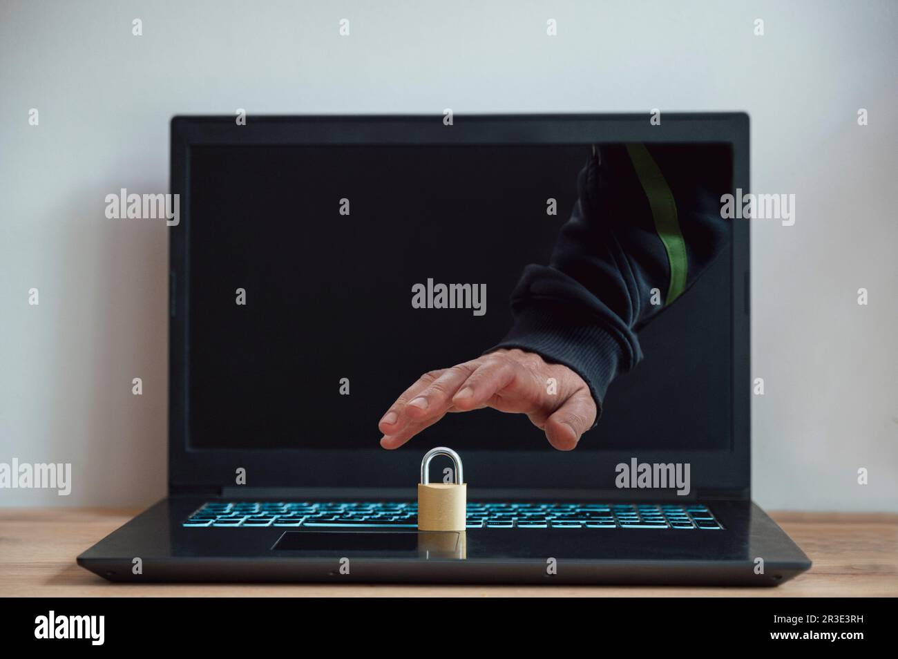Männliche Hand, die aus einem Laptop-Bildschirm greift und versucht, ein goldenes Vorhängeschloss zu stehlen, in einem konzeptionellen Bild von Online-Cyberdiebstahl und Sicherheitsproblemen. Stockfoto