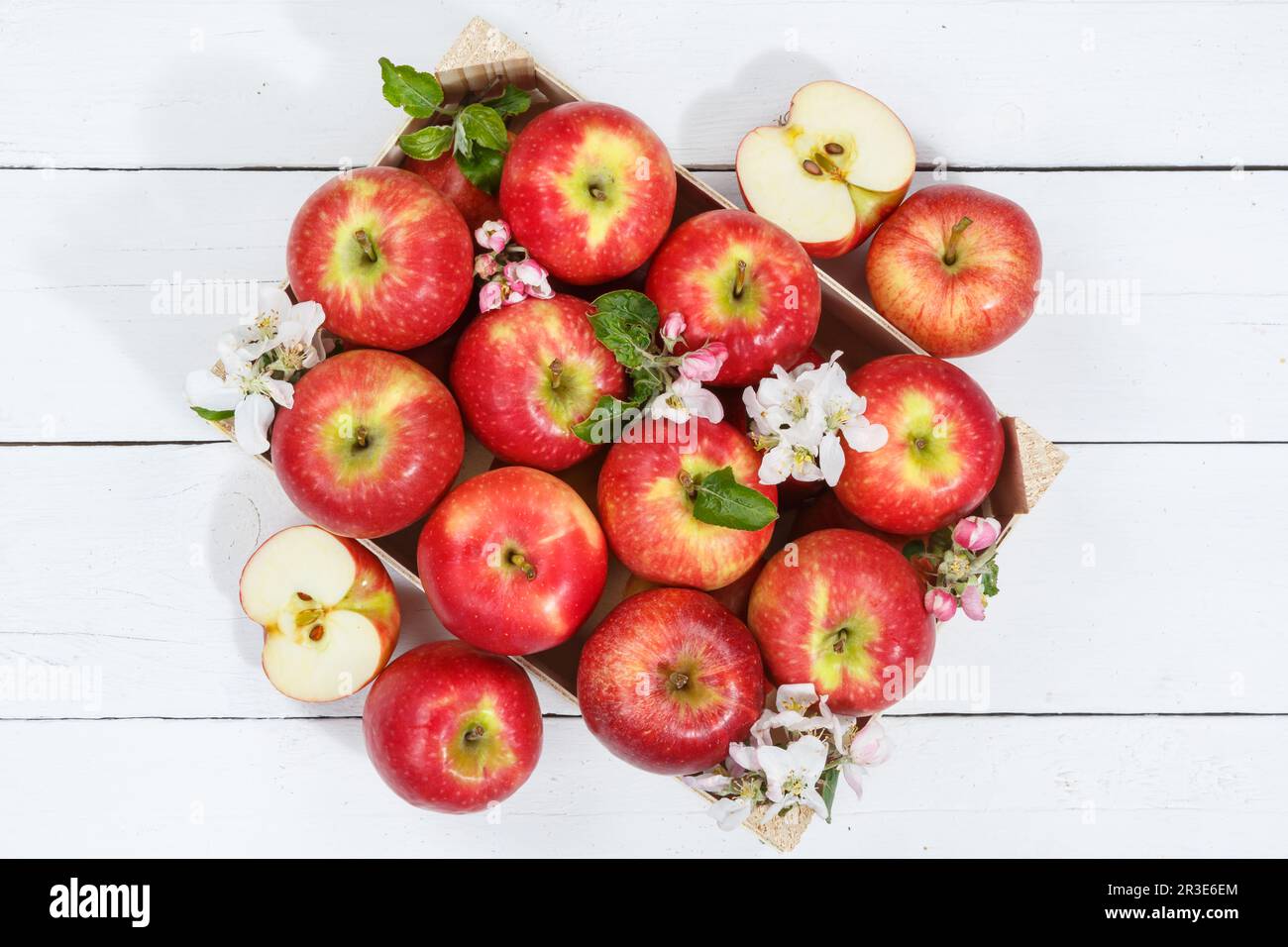 Äpfel Früchte rote Apfelfrucht Box auf Holzbrett mit Blumen und Blättern Stockfoto
