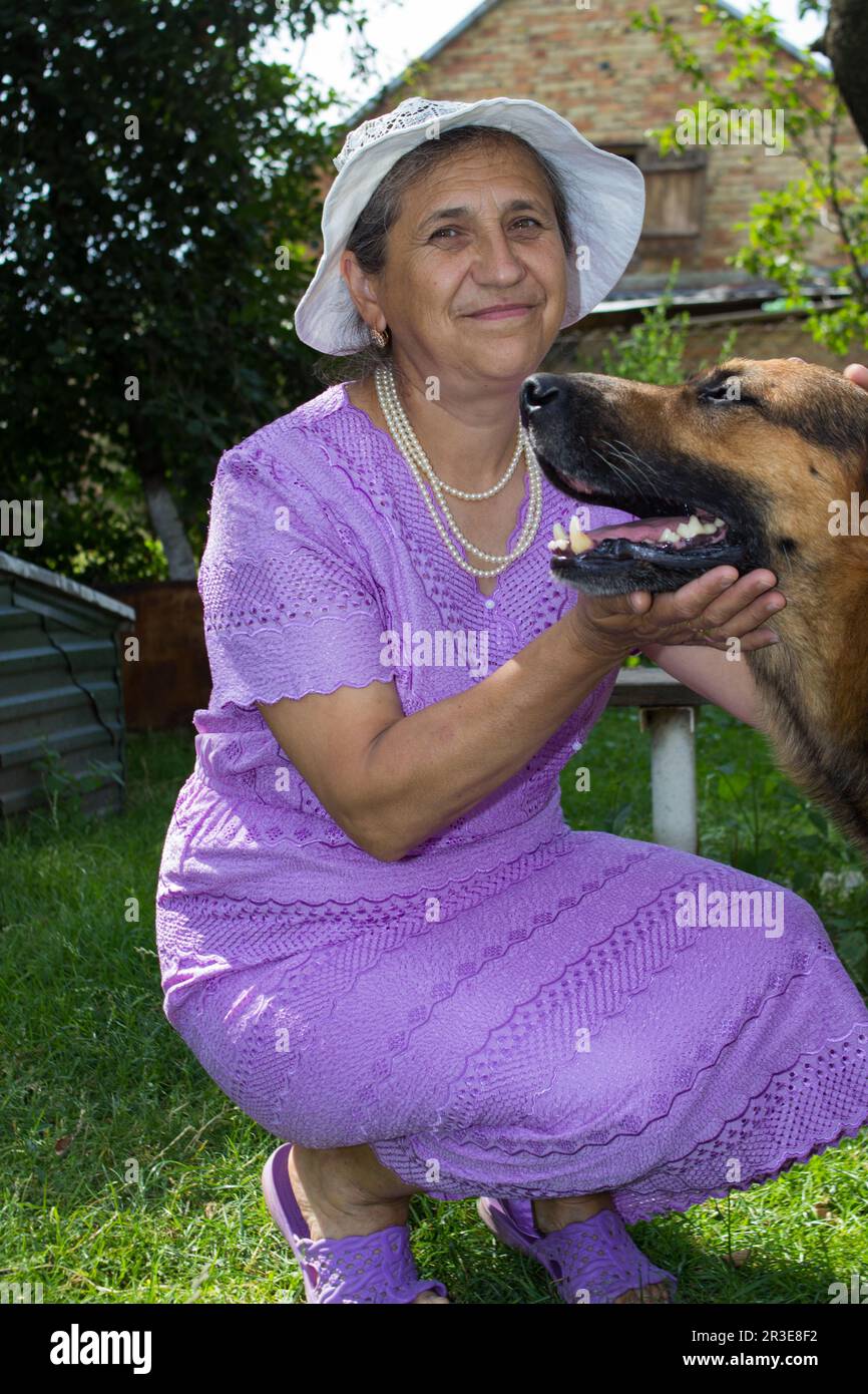 Lächelnde Rentnerin mit deutschem Schäferhund auf dem Land Stockfoto
