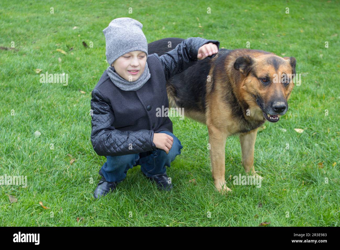Auf dem Gras umarmte der Junge einen Hund im Garten Stockfoto