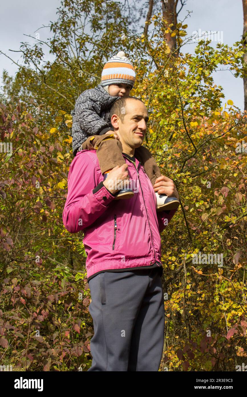 Der Herbstvater trägt im Wald einen kleinen Knabenhals Stockfoto