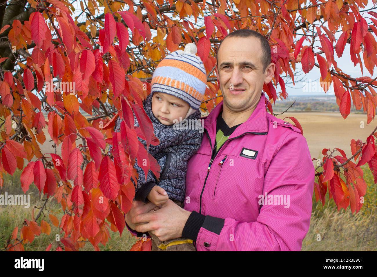 Herbstkirschen, der Vater hält seinen Sohn in den Armen Stockfoto