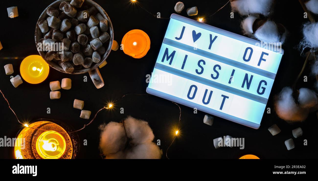 Lightbox mit Text JOMO Joy of Missing Out. Entspannungsbegriff aus Information und Gadgets. Draufsicht. Flach verlegt. Tasse mit Stockfoto