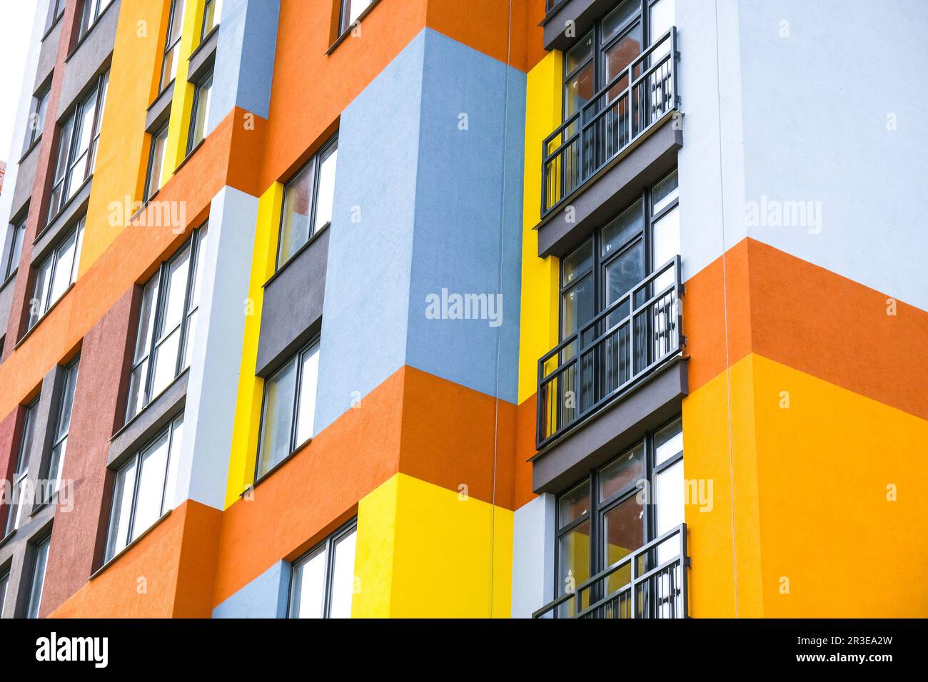 Moderner Gebäudewinkel und Fenster. Mehrstöckiges neues mehrfarbiges Apartmentgebäude. Stilvolle Wohnungen. Leuchtend saftiges C Stockfoto