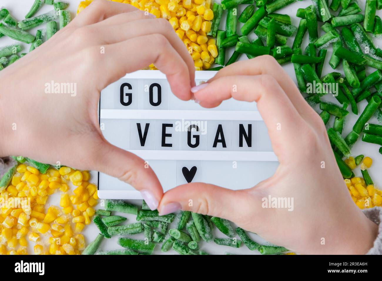Lightbox mit Text GO VEGANES Tiefkühlgemüse Lebensmittel aus gelbem Mais, grünen Bohnen. Ernte Konservierung von Lebensmitteln für den Winter. Stockfoto