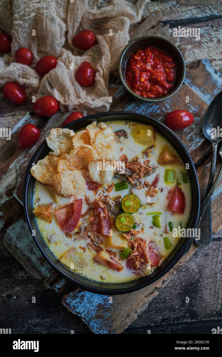 Soto Betawi ist eine indonesische Suppe aus Kokosmilch, die mit Rindfleisch, Kartoffeln und Tomaten gefüllt ist Stockfoto