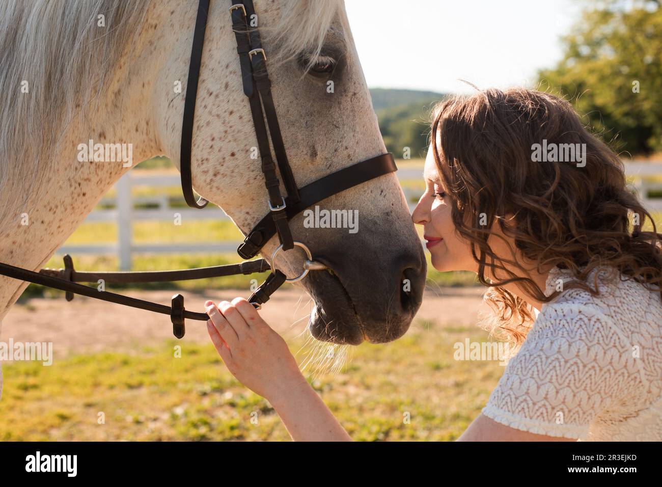 Die Frau mit lockigen Haaren huddelt an ihr Pferd Stockfoto