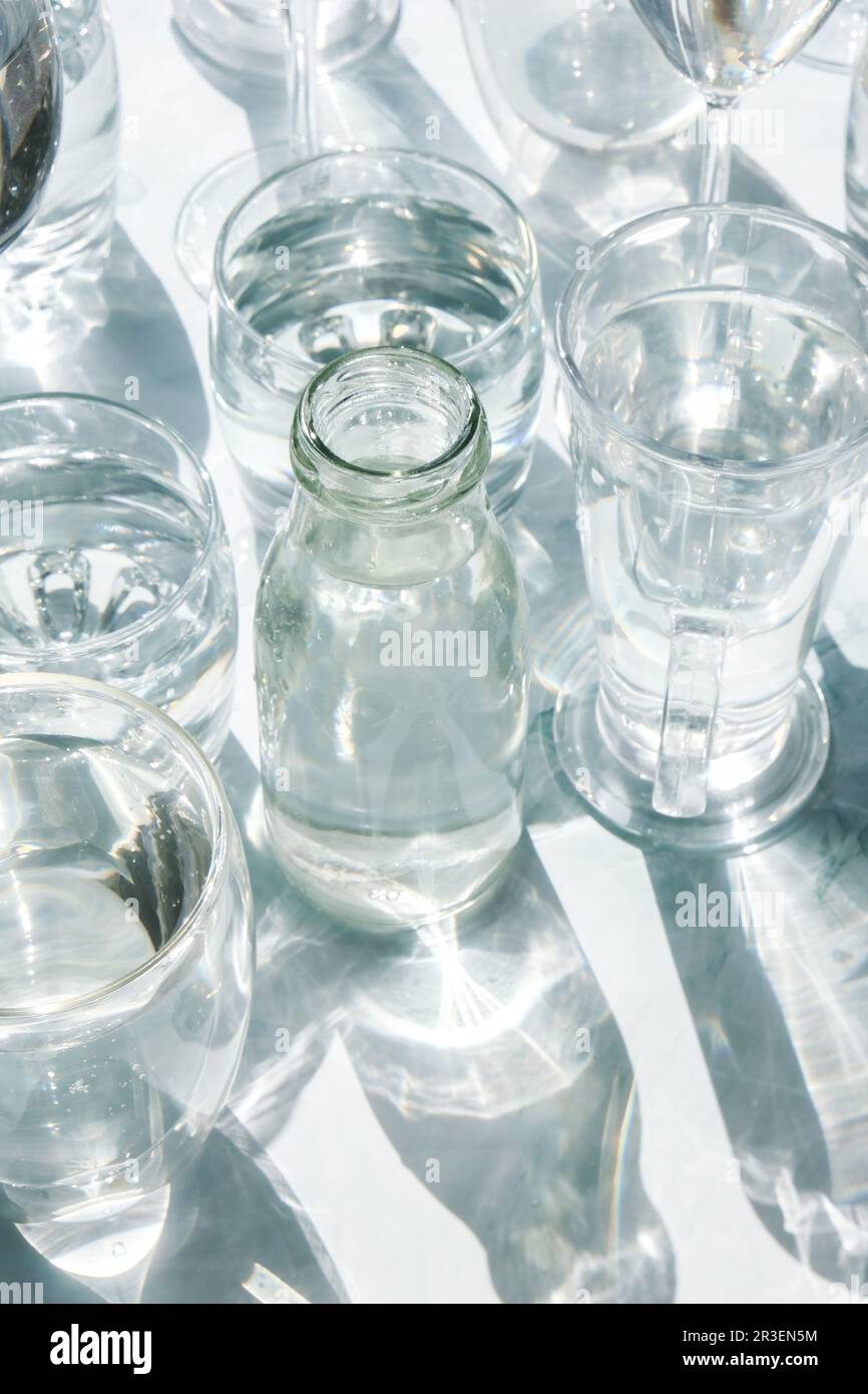 Wunderschöne verschiedene Brillen stehen auf weißem Hintergrund im Sonnenlicht und erzeugen Schatten. Hartes Licht, lange Schatten. Kreatives Konzept Stockfoto