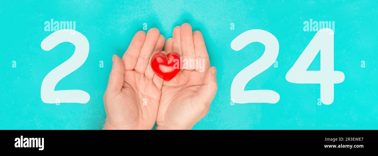 Neujahr 2024, Kalenderdatum, rotes Herz in den Händen, Wohltätigkeitskonzept, neue Ziele und Auflösung Stockfoto