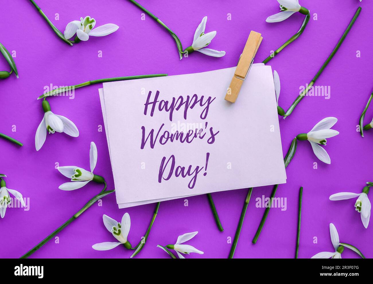 Grußkarte mit Schriftzug „Happy Womens Day“. Frühlingsblumen Schneeglöß. Schöner zarter Blumenstrauß. Urlaubskonzept Stockfoto