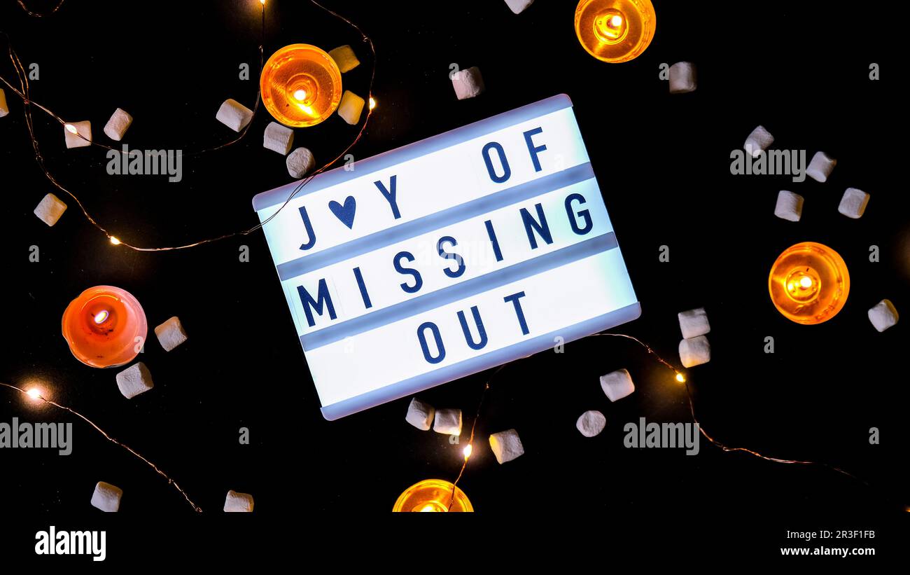 Lightbox mit Text JOMO Joy of Missing Out. Entspannungsbegriff aus Information und Gadgets. Draufsicht. Flach verlegt. Teelicht Stockfoto